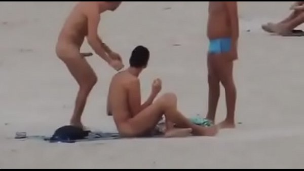 Cara com pau duro na praia beijando outro macho.